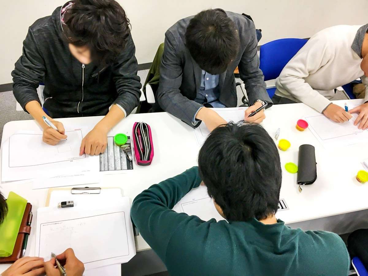 机を囲んで、ワークシートに書き込む参加者